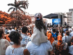 tante persone che assistono a un concerto, una bimba sulle spalle di un uomo