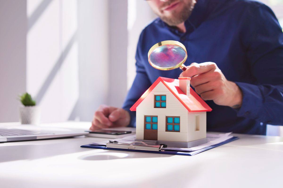 Persona che guarda una casa in miniatura con la lente