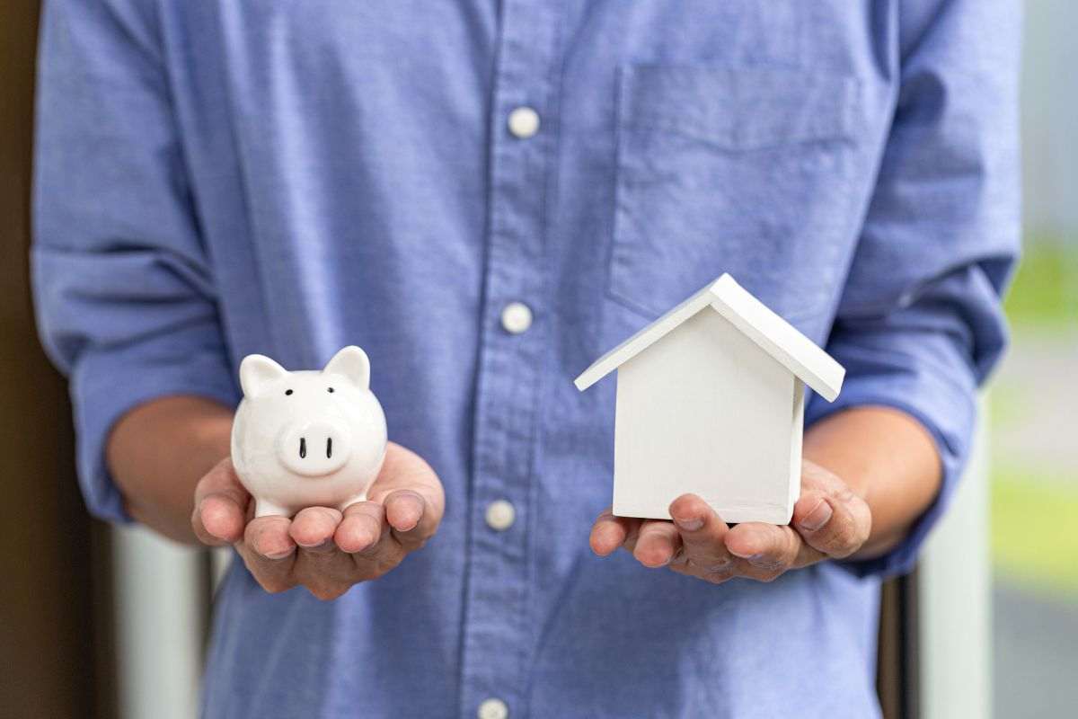 persona che mantiene uns sallvadanaio e la miniatura di una casa