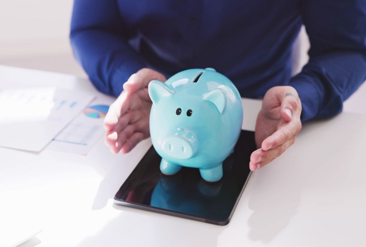 Persona che mantiene un salvadanaio turchese fra le mani